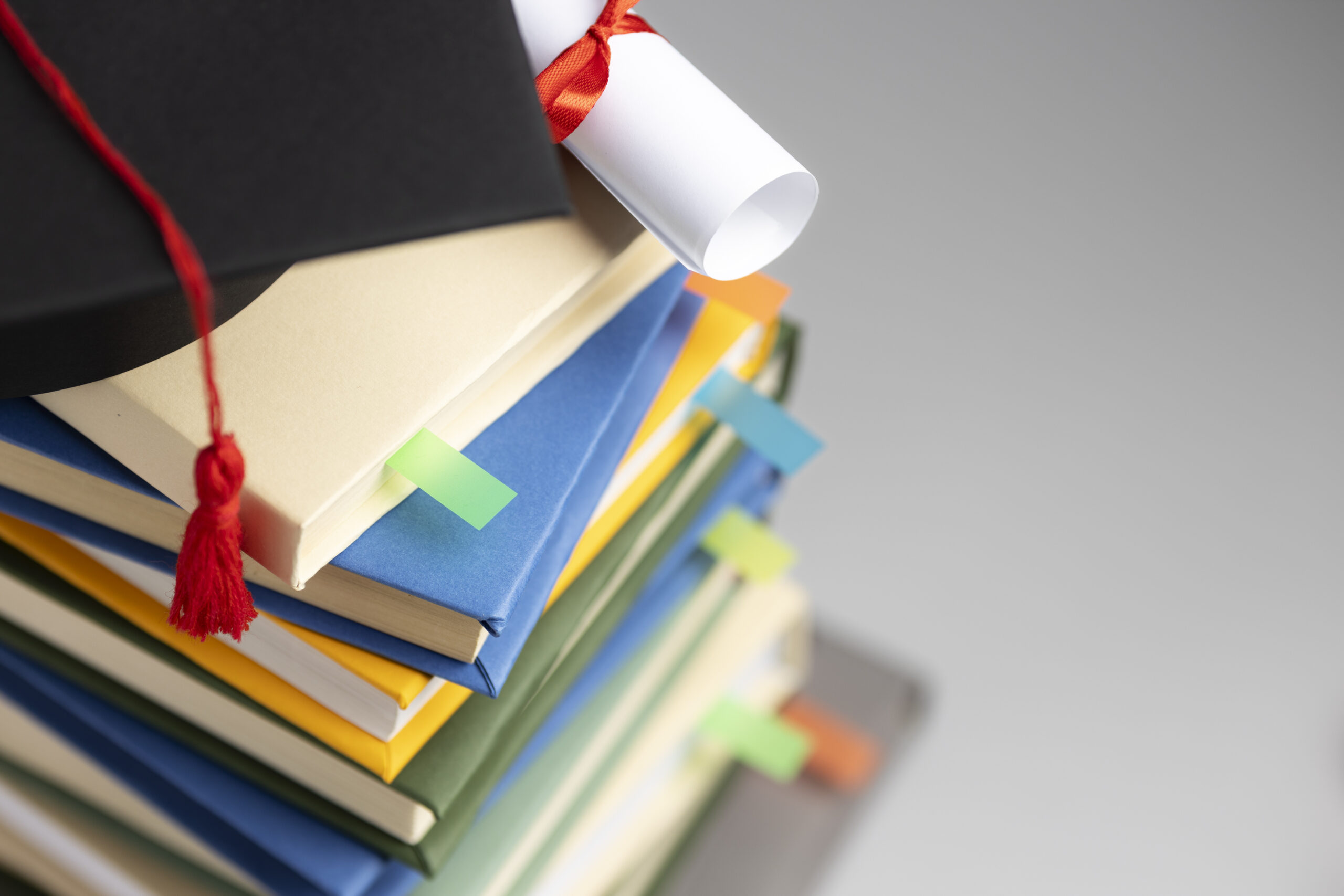 alto-angolo-di-libri-impilati-un-cappello-di-laurea-e-un-diploma-per-la-giornata-dell-istruzione